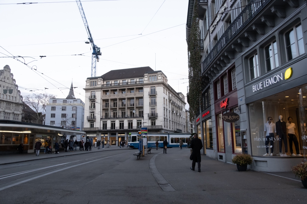 Paradeplatz: shops on the side of the square, tram line, tram and crane.