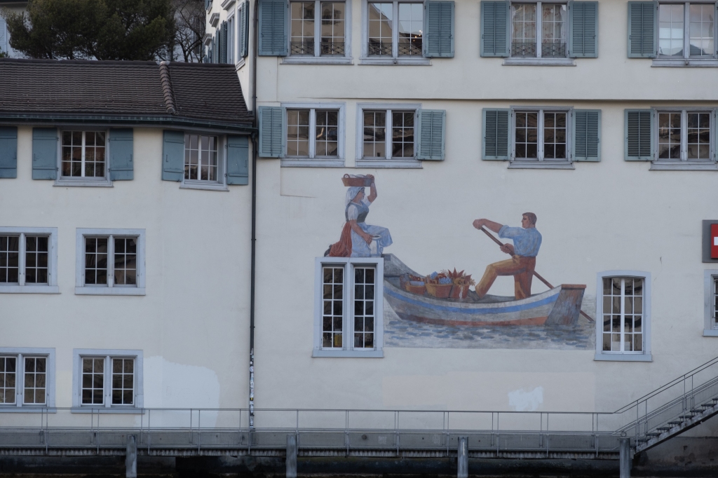 Façade of the Schweizer Heimatwerk, with a wall painting by Wilhelm Hart showing a man on a rowboat and a woman holding goods on her head.