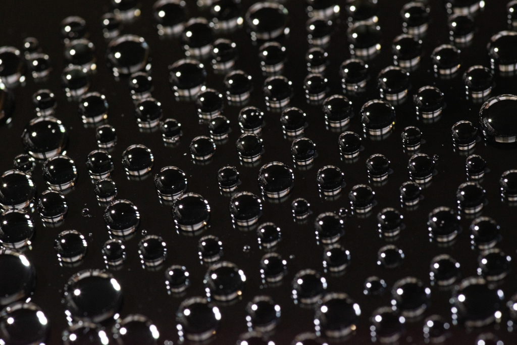 A larger field of small droplets of water over a black background.