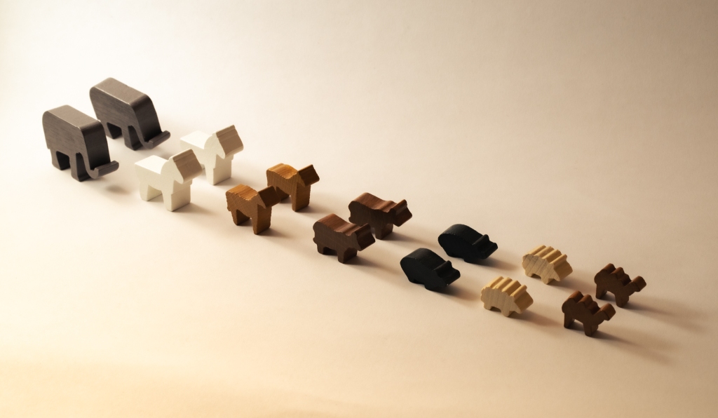 Pairs of wooden animals aligned as if they are queuing. From front to back: tiny camels, sheep, pigs, cows, donkeys, horses and elephants.